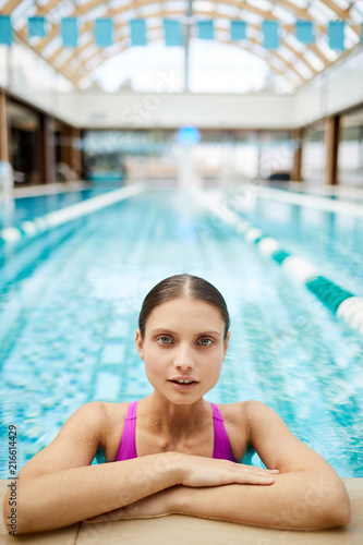 Young healthy woman in swimsuit looking out of swimming-pool while relaxing © pressmaster