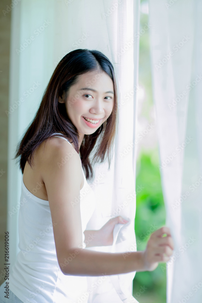 Asian girl opening the white curtain
