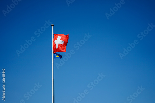 national flag of switzerland and kosova with blue sky background