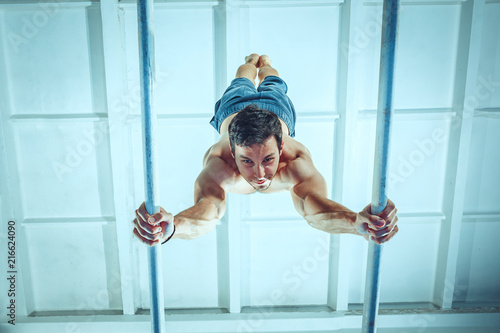 The sportsman performing difficult gymnastic exercise at gym. The sport, exercise, gymnast, health, training, athlete concept. Caucasian fit model