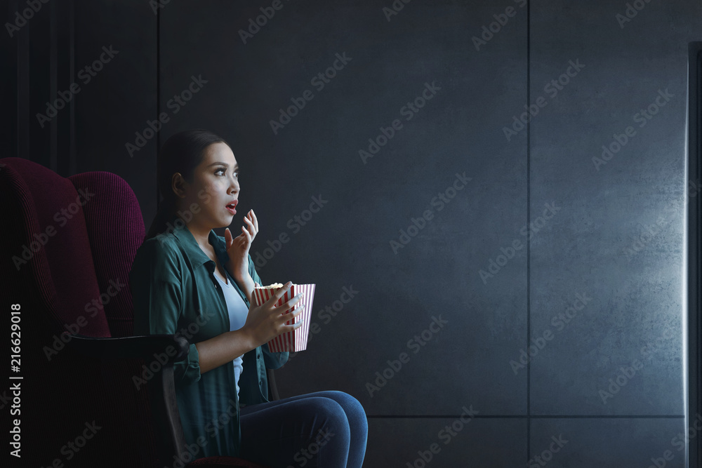 Fototapeta premium Portrait of asian woman with popcorn watching horror movie