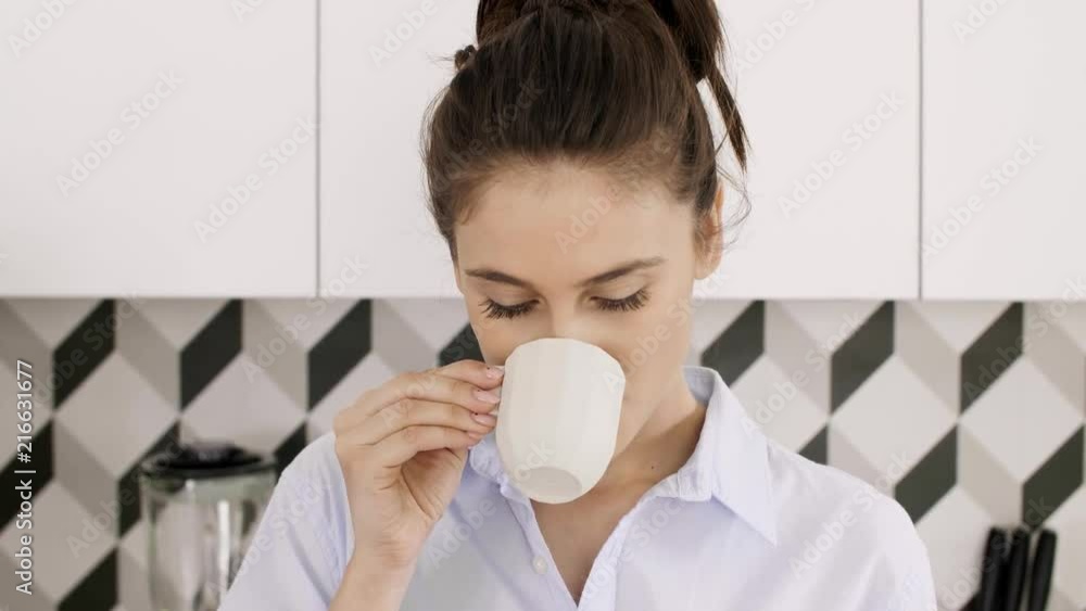 Portrait of woman drinking coffee or tea in her kitchen Portrait of woman drinking coffee or tea in her kitchen