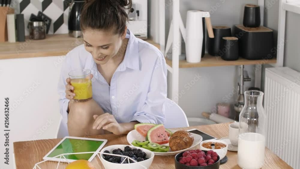 Young woman using a tablet during breakfast Young woman using a tablet during breakfast