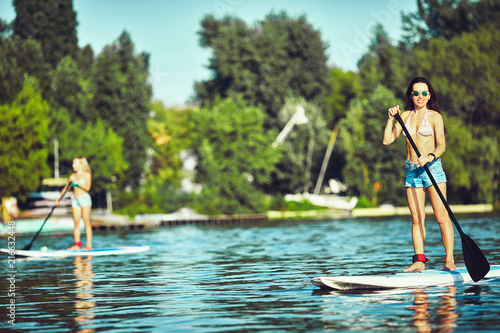 SUP Stand up Surf girl with paddle at sunset