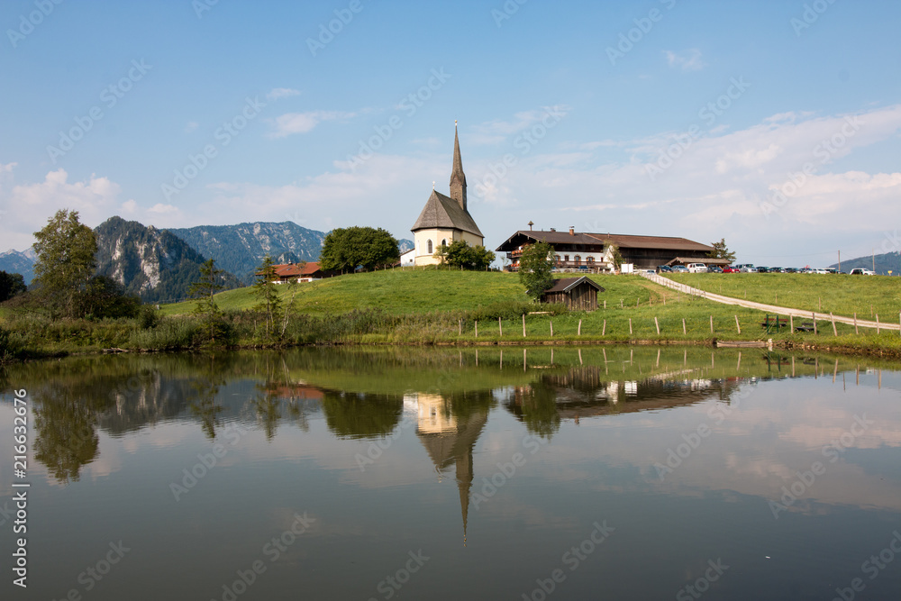 Inzell, Germany - August 5, 2018: View of the Nikolauskirche church in the Bavarian community of Inzell with the Alps in the background.