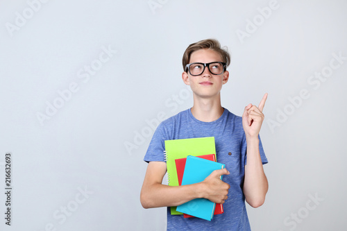 Young boy with books on grey background