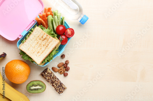 School lunch box with fruits and vegetables on wooden table