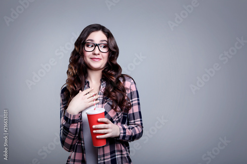 Young beautiful woman with paper cup on grey background