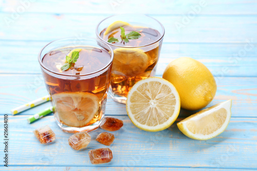 Ice tea in glasses with lemon and mint leafs on wooden table