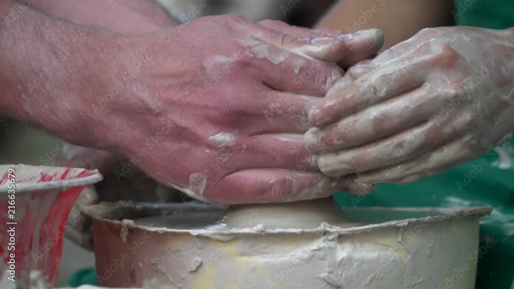 Close up of hands working clay on potter's wheel. Potter shapes the clay product with pottery tools on the potter's wheel