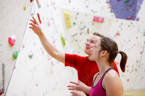 Photo of young female athlete and man on wall background for rock climbing
