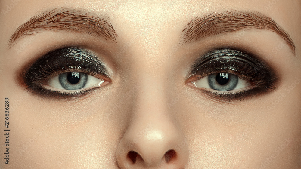 Fototapeta premium Beautiful macro shot of female eye with extreme long eyelashes and black liner makeup. Perfect shape make-up and long lashes. Cosmetics and make-up. Closeup macro shot of fashion eyes visage