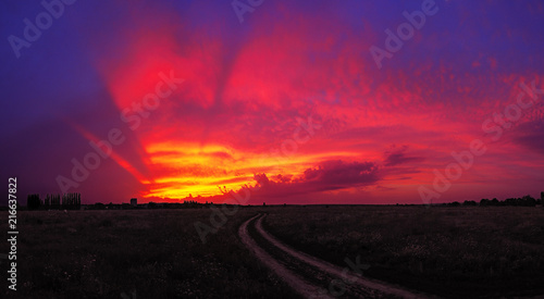 Sunset over the field with road at the village colorful