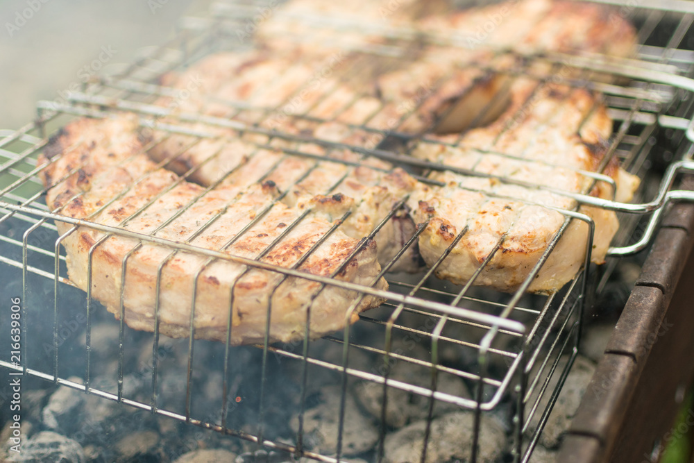 Large pieces of pork ribs on the grill. Preparation of meat roasted on coals.
