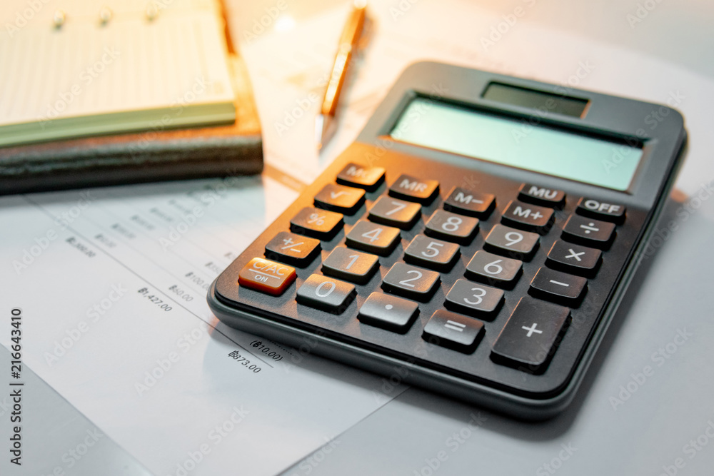 Calculator, pen, blank lined paper page of notebook and summary report paperwork with bar graph and table. Financial data analysis. Business planning and management concept Calculator, pen, blank lined paper page of notebook and summary report paperwork with bar graph and table. Financial data analysis. Business planning and management concept