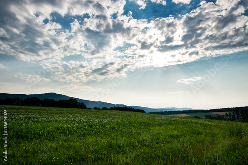 Field with mountains in the background and Clouds on the sky in the bavarian forest