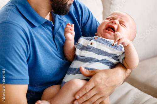 Father holding baby boy crying