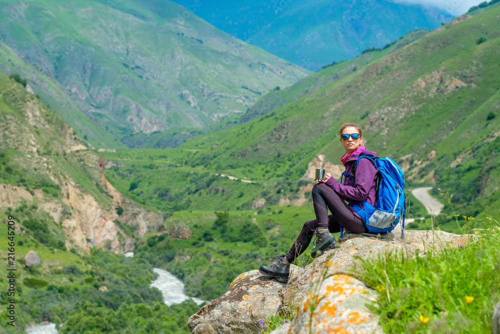 Fototapeta premium Young woman in the mountains with a backpack. Mountain landscape. River in the valley.