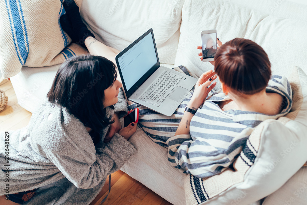 Women relaxing on sofa using laptop Women relaxing on sofa using laptop