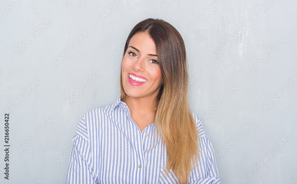 Young adult woman over grunge grey wall wearing business shirt happy face smiling with crossed arms looking at the camera. Positive person. Young adult woman over grunge grey wall wearing business shirt happy face smiling with crossed arms looking at the camera. Positive person.