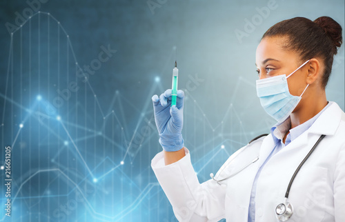 healthcare and medicine concept - close up of african female doctor in surgical mask with syringe over blue background and diagrams charts holograms