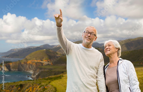 old age, tourism, travel and people concept - happy senior couple over bixby creek bridge on big sur coast of california background