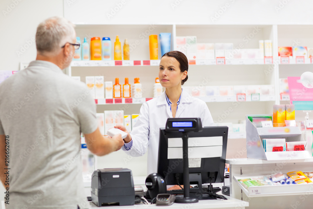 medicine, pharmaceutics, health care and people concept - apothecary giving drug to senior man customer at drugstore