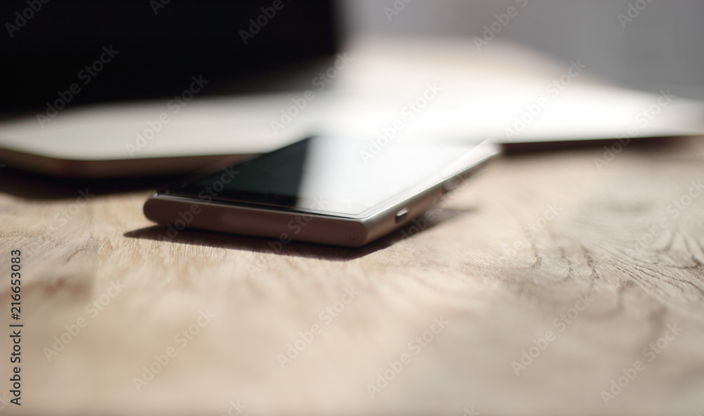 close up. blurred image of a mobile phone and laptop on the desk close up. blurred image of a mobile phone and laptop on the desk