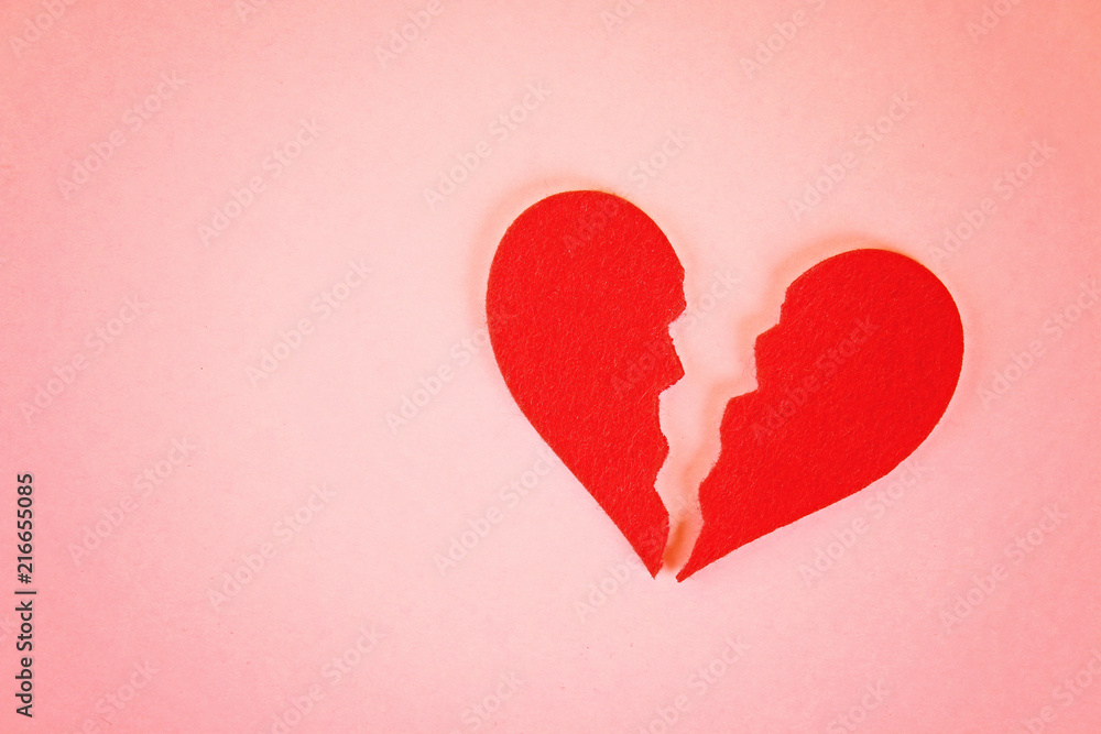 Red felt heart broken into two halves on a pink background. Red felt heart broken into two halves on a pink background.