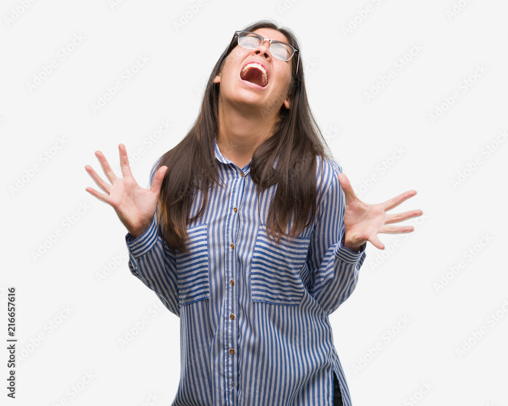 Young beautiful hispanic business woman crazy and mad shouting and yelling with aggressive expression and arms raised. Frustration concept. Young beautiful hispanic business woman crazy and mad shouting and yelling with aggressive expression and arms raised. Frustration concept.