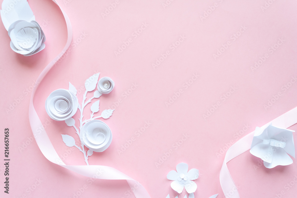 frame with white paper flowers and pink ribbon on pink background. Cut from paper.