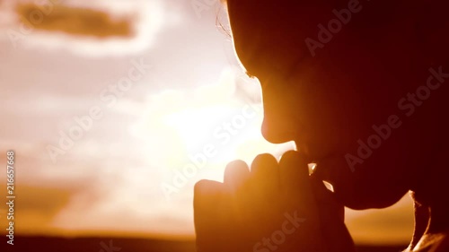 the girl prays. Girl folded her hands in prayer silhouette at sunset. slow motion video. Girl folded her lifestyle hands in prayer pray to God. girl praying asks forgiveness for sins of repentance photo