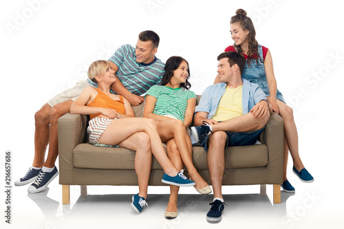 friendship, leisure and people concept - group of happy smiling friends sitting on sofa over white background © Syda Productions