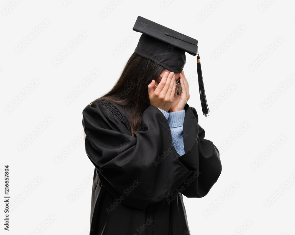 Young hispanic woman wearing graduated cap and uniform with sad expression covering face with hands while crying. Depression concept.