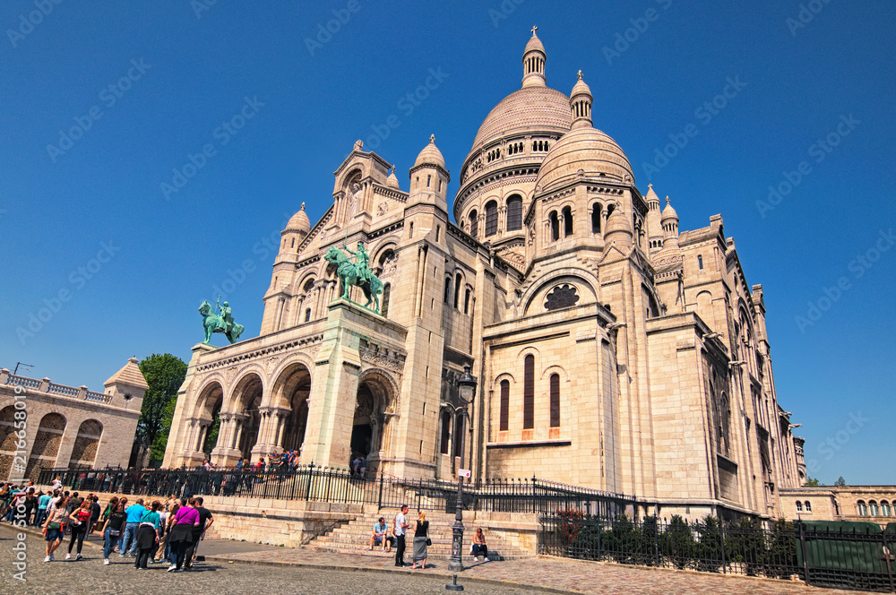 Paris, France-MAY 06, 2018: Sacre Coeur Basilica in spring sunny day. Large medieval cathedral. People are standing in line to get inside. Famous touristic place and travel destination in Europe