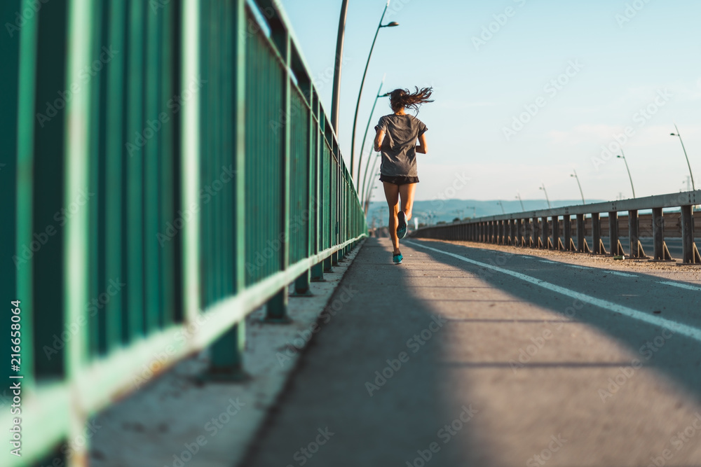 Back view of athletic woman jogging on the street