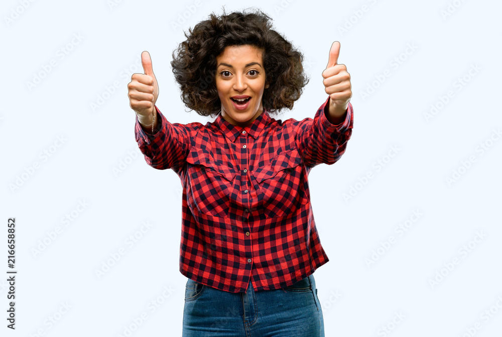 Beautiful arab woman stand happy and positive with thumbs up approving with a big smile expressing okay gesture Beautiful arab woman stand happy and positive with thumbs up approving with a big smile expressing okay gesture