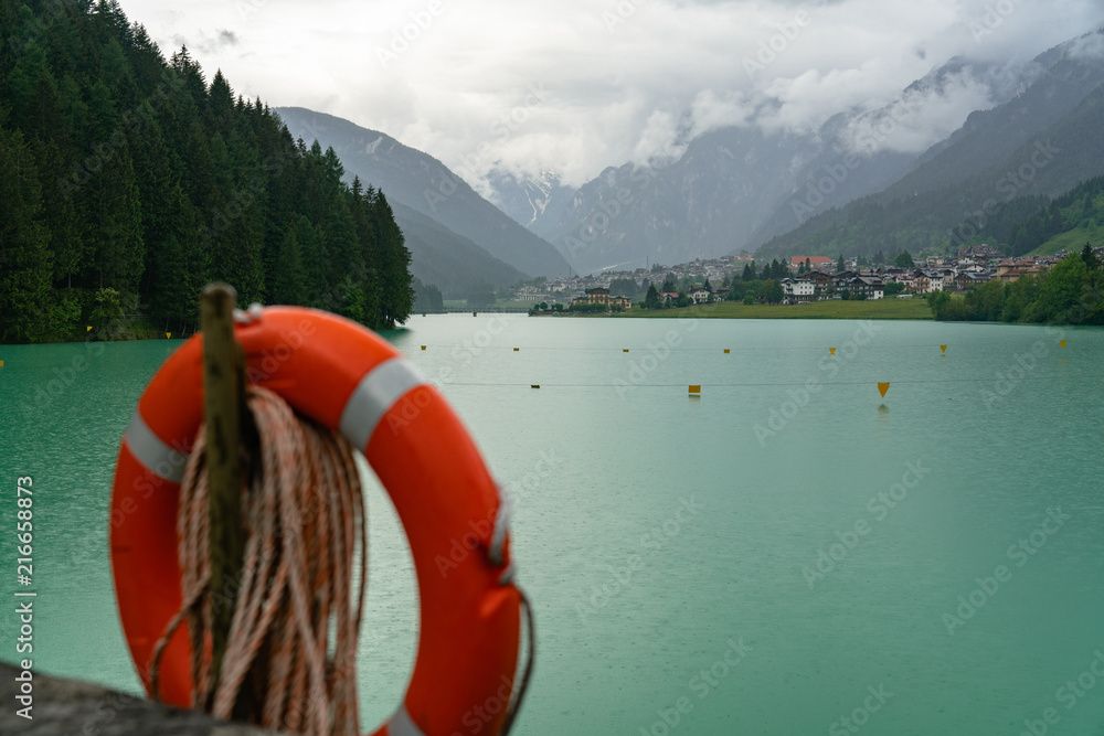 Red life ring at Santa Caterina lake among mountains in Italy blue water