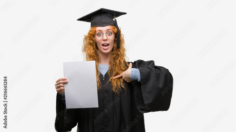 Young redhead woman wearing graduate uniform holding degree with surprise face pointing finger to himself Young redhead woman wearing graduate uniform holding degree with surprise face pointing finger to himself