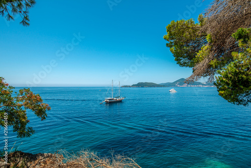 Piękna zatoka morska w lecie. Jacht na tle wyspy St Stefan Morze Adriatyckie, Czarnogóra.