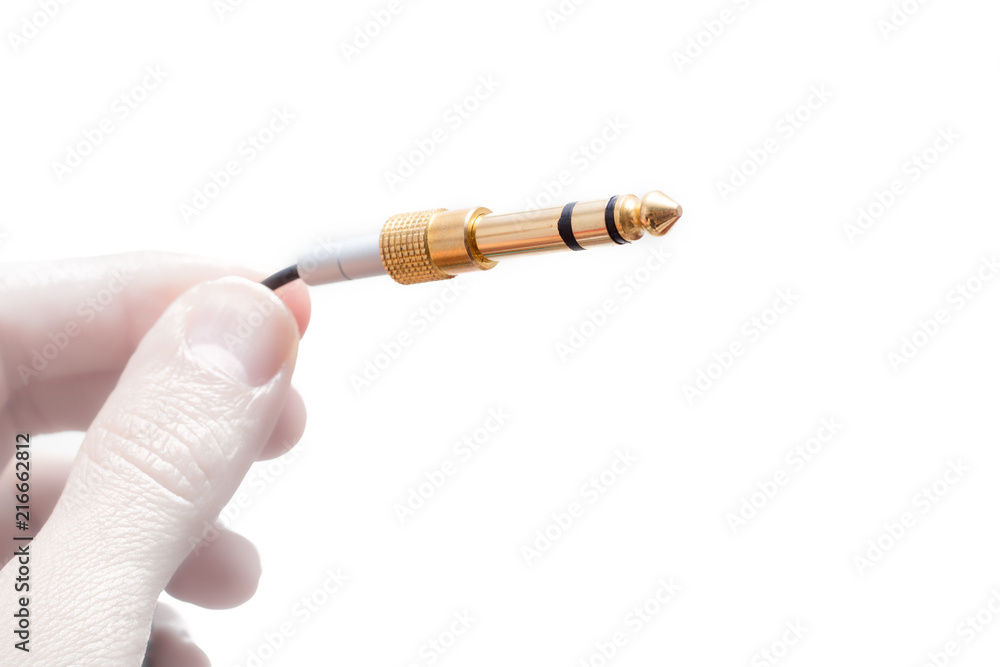 Hand with stereo audio cable gold coated adapter isolated on white background Hand with stereo audio cable gold coated adapter isolated on white background