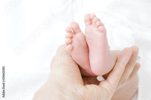 Parent holding in the hand feet of newborn baby on white background © Onuro