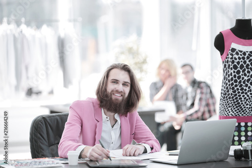 smiling fashion Designer at the table in a modern Studio
