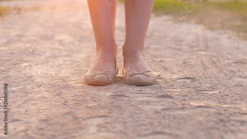 Woman feet in flat shoes jump in road dust.