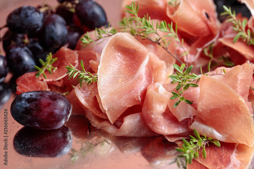 Italian prosciutto crudo or jamon with thyme and grapes.