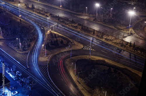 Illuminated motorway junction by night with blue and red light traces