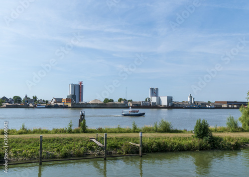 River with factory on the bank and passing boat. Schoonhoven  The Netherlands.