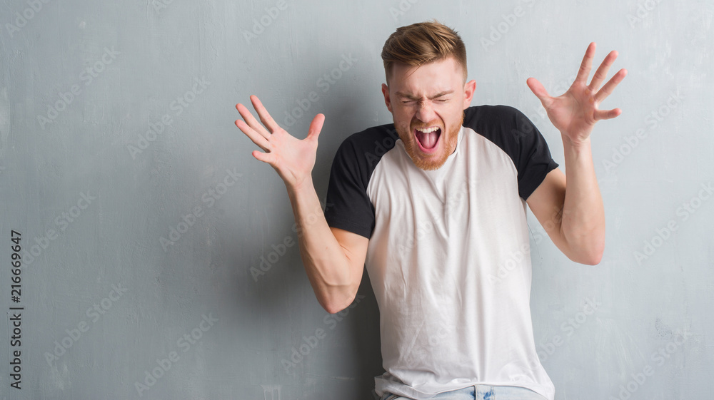 Young redhead man over grey grunge wall celebrating mad and crazy for success with arms raised and closed eyes screaming excited. Winner concept Young redhead man over grey grunge wall celebrating mad and crazy for success with arms raised and closed eyes screaming excited. Winner concept