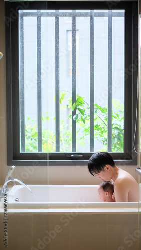 Asian father and little baby take a long soak in the bathtub with love and caring.