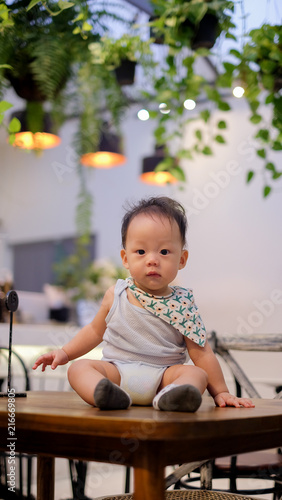 The Asian baby sitting on the table with happiness.